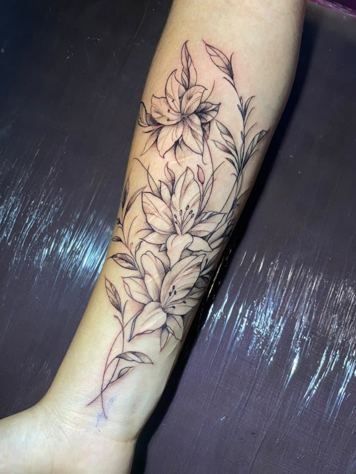 Tatuagem de lírios em traço fino no antebraço